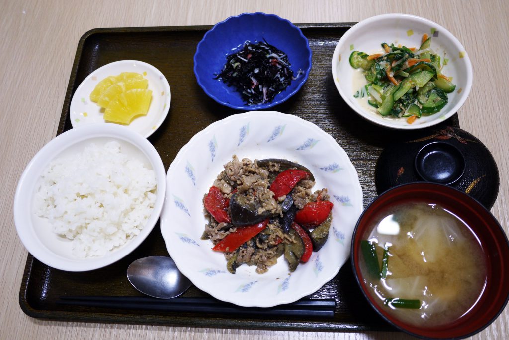 きょうのお昼ごはんは、なすと豚肉の鍋しぎ、青菜和え、ひじきの酢の物、みそ汁、果物でした。