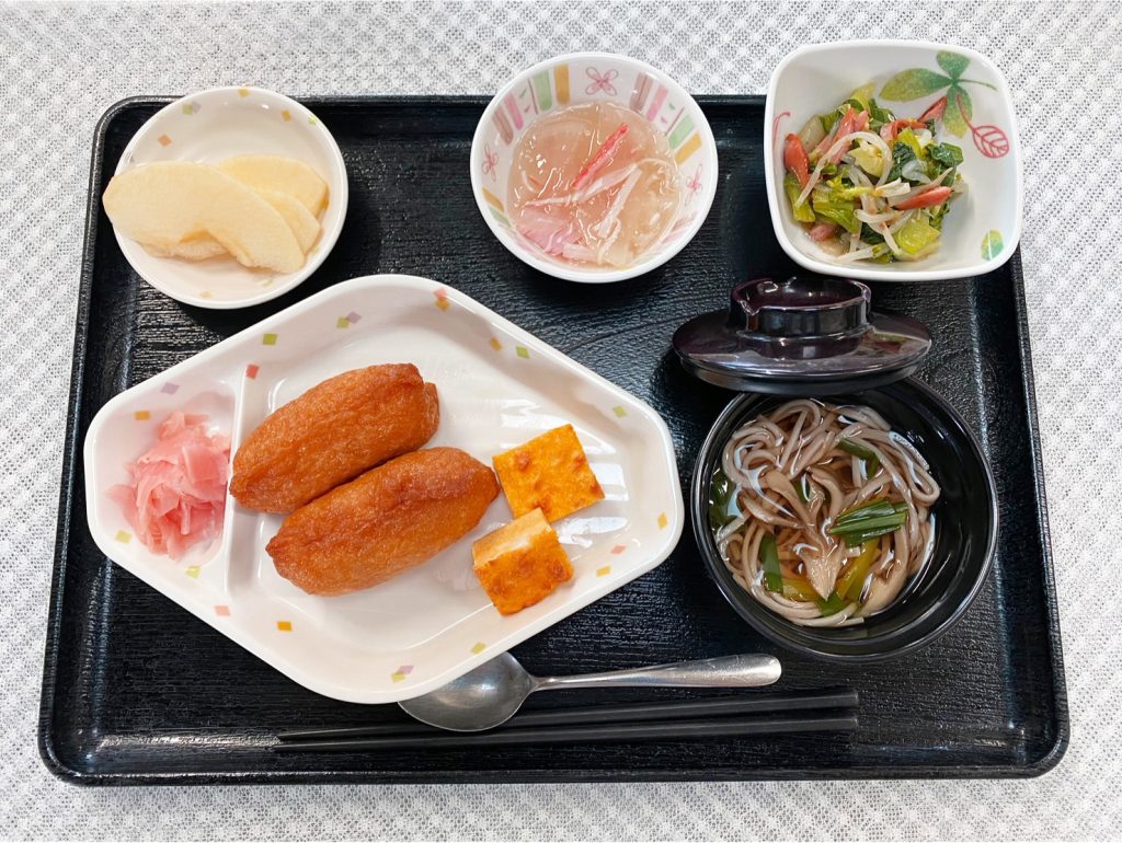12月29日木曜日　きょうのお昼ごはんは、おそば・いなり寿司・はんぺんのピカタ・和え物・みそ汁・くだものでした。