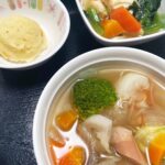 3月7日金曜日　きょうのお昼ごはんは、ウインナーと根菜のスープ煮・コーンポテト・含め煮・くだものでした。